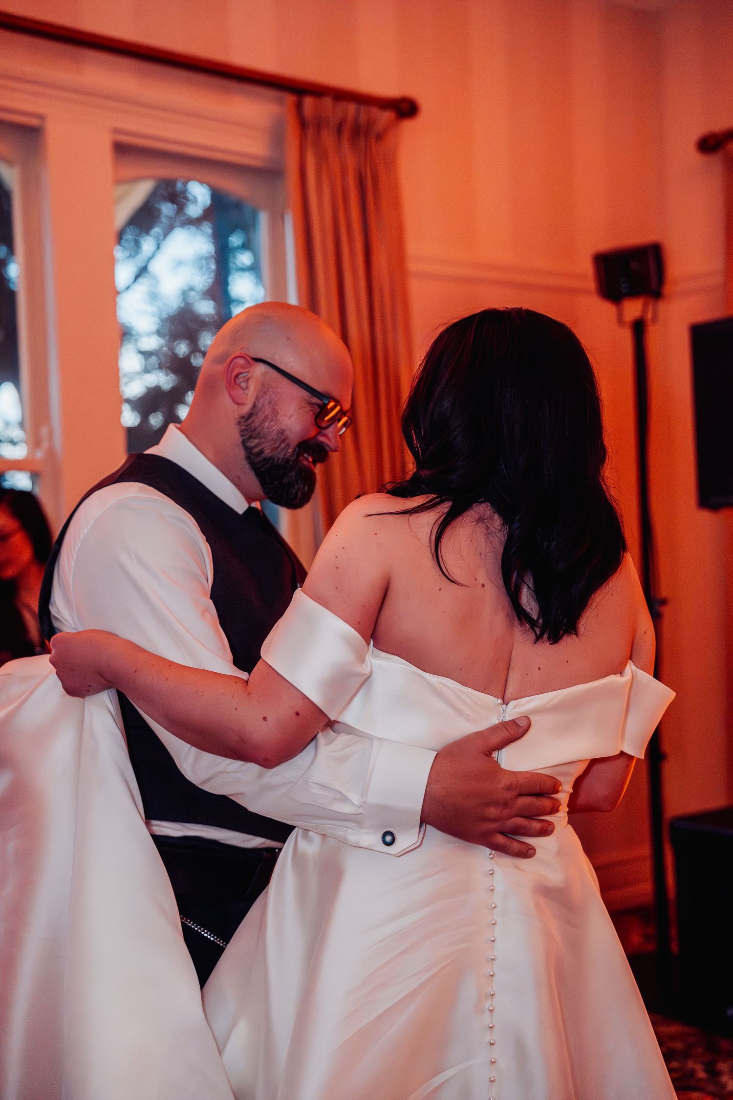 Bride and groom share an intimate first dance in warmly lit wedding reception venue.