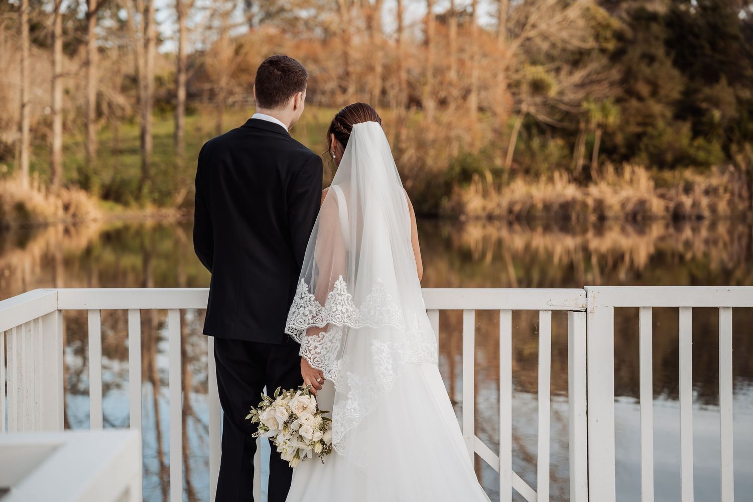 White wedding gazebo overlooking a serene lake with autumn trees in the background.