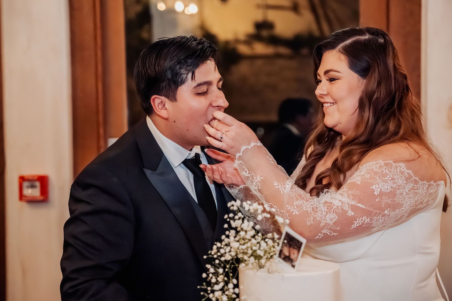 A tender moment between newlyweds as they share cake during their wedding reception.