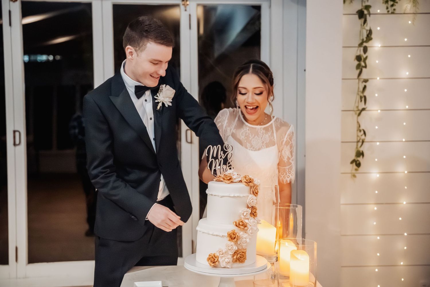 A couple celebrates their wedding reception by cutting into an elegantly decorated cake.