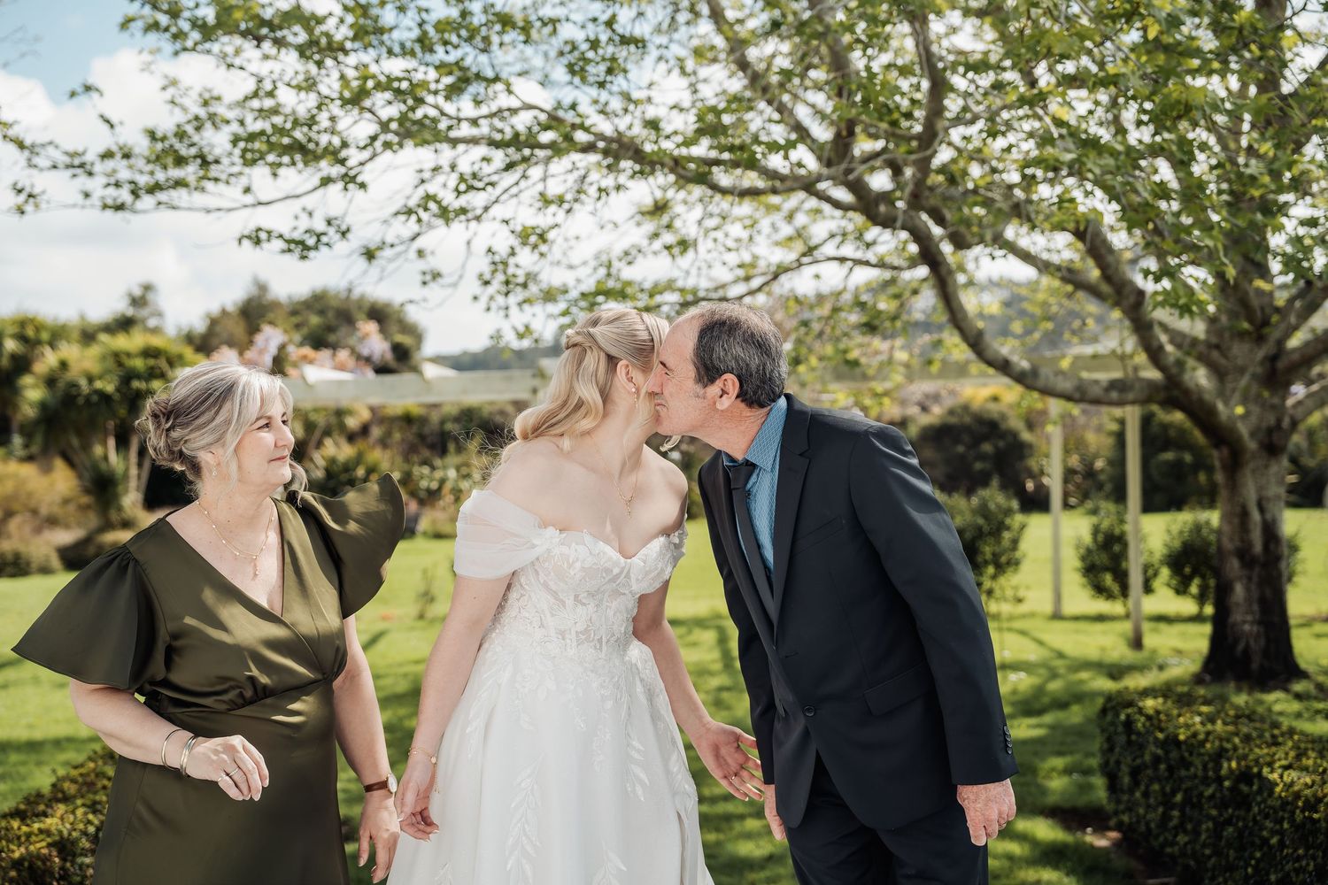 Wedding party walking together through a lush green garden landscape.