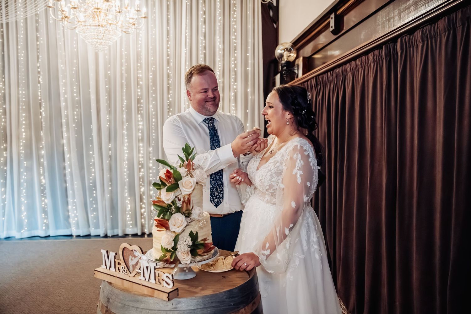Wedding reception venue decorated with string lights and elegant curtains.