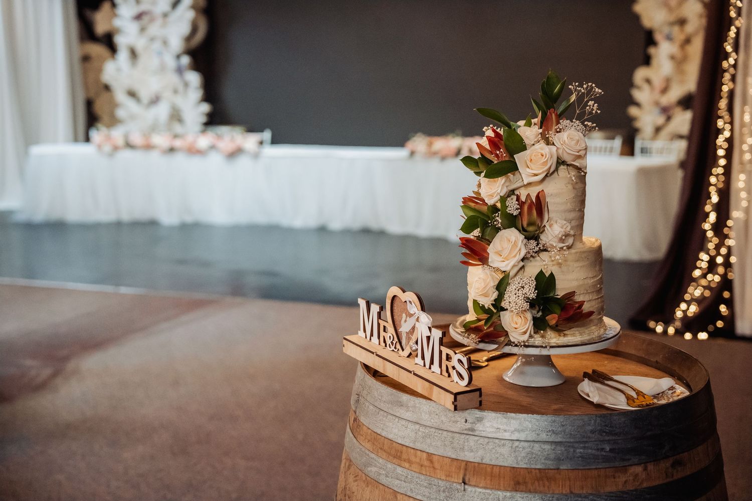 Elegant wedding reception table with rustic decor, floral arrangements, and twinkling lights overhead.