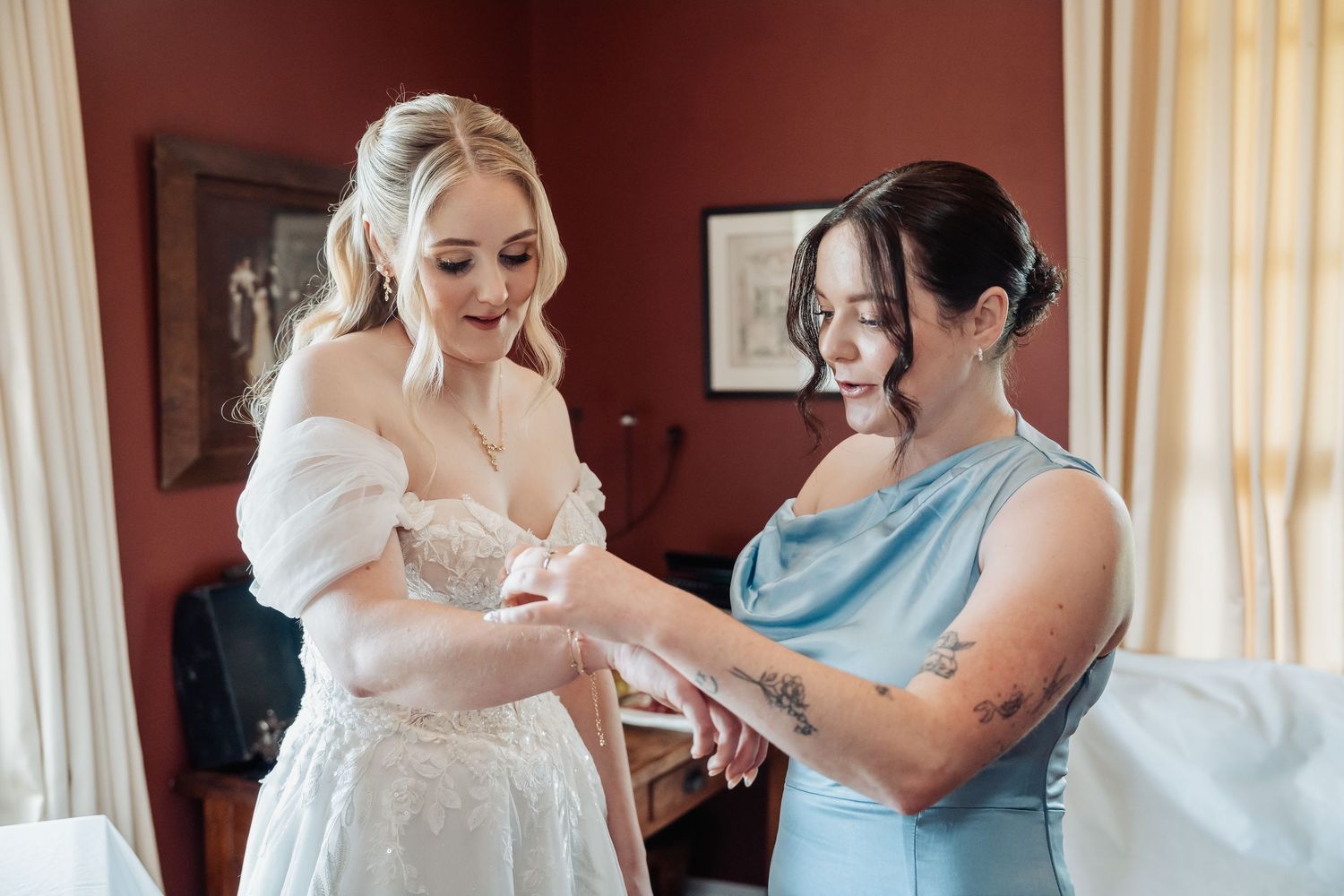 Wedding preparation scene in an elegant room with soft natural lighting and white decor.