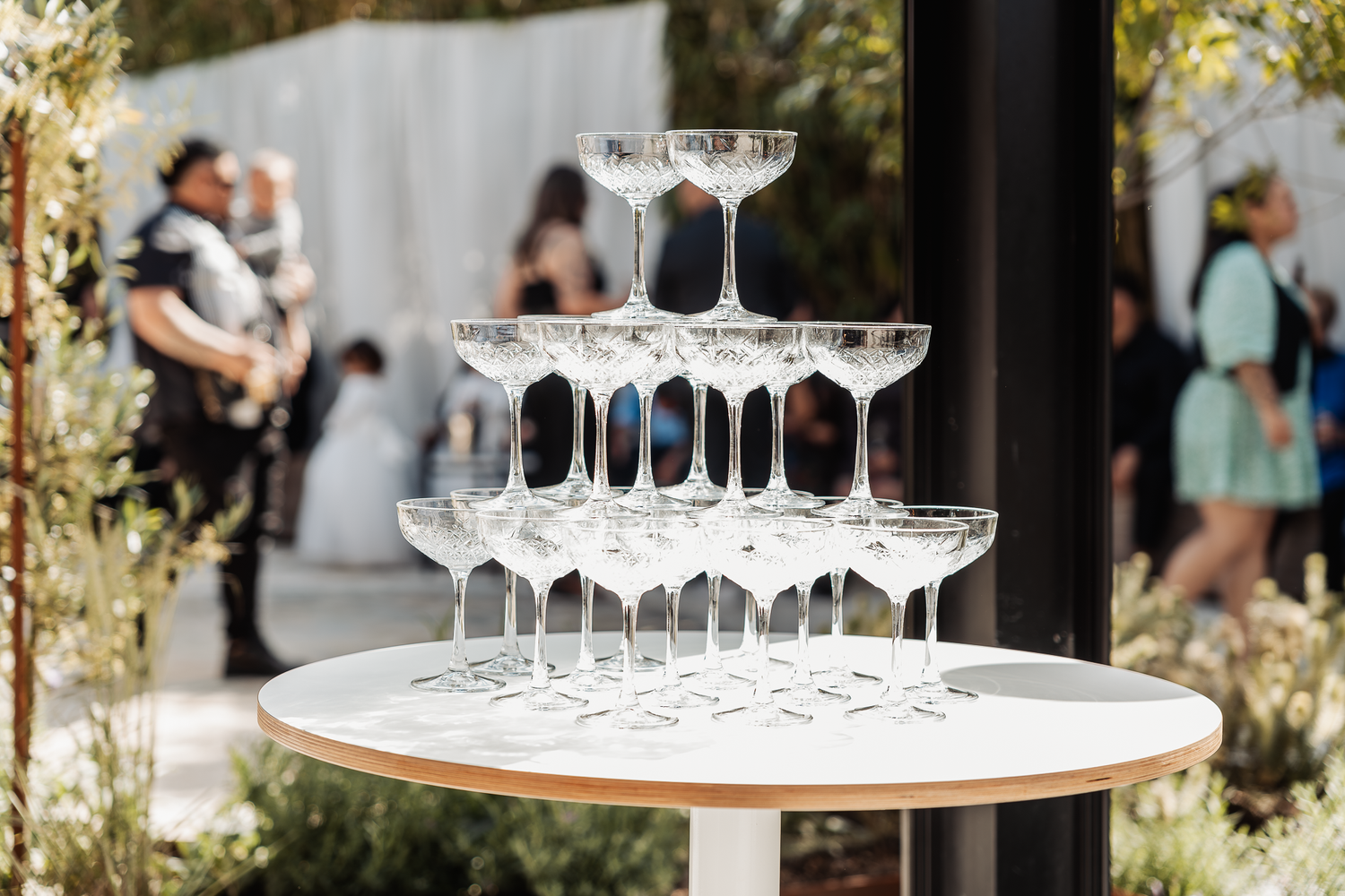 Elegant champagne tower display with empty glasses at outdoor wedding reception.