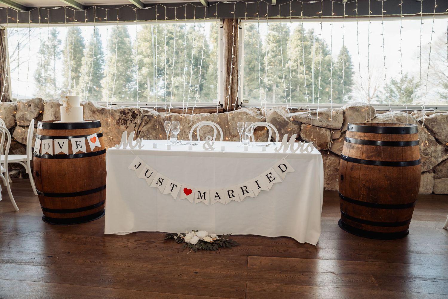Rustic barn wedding reception setup with wooden barrels and white decorative banners.