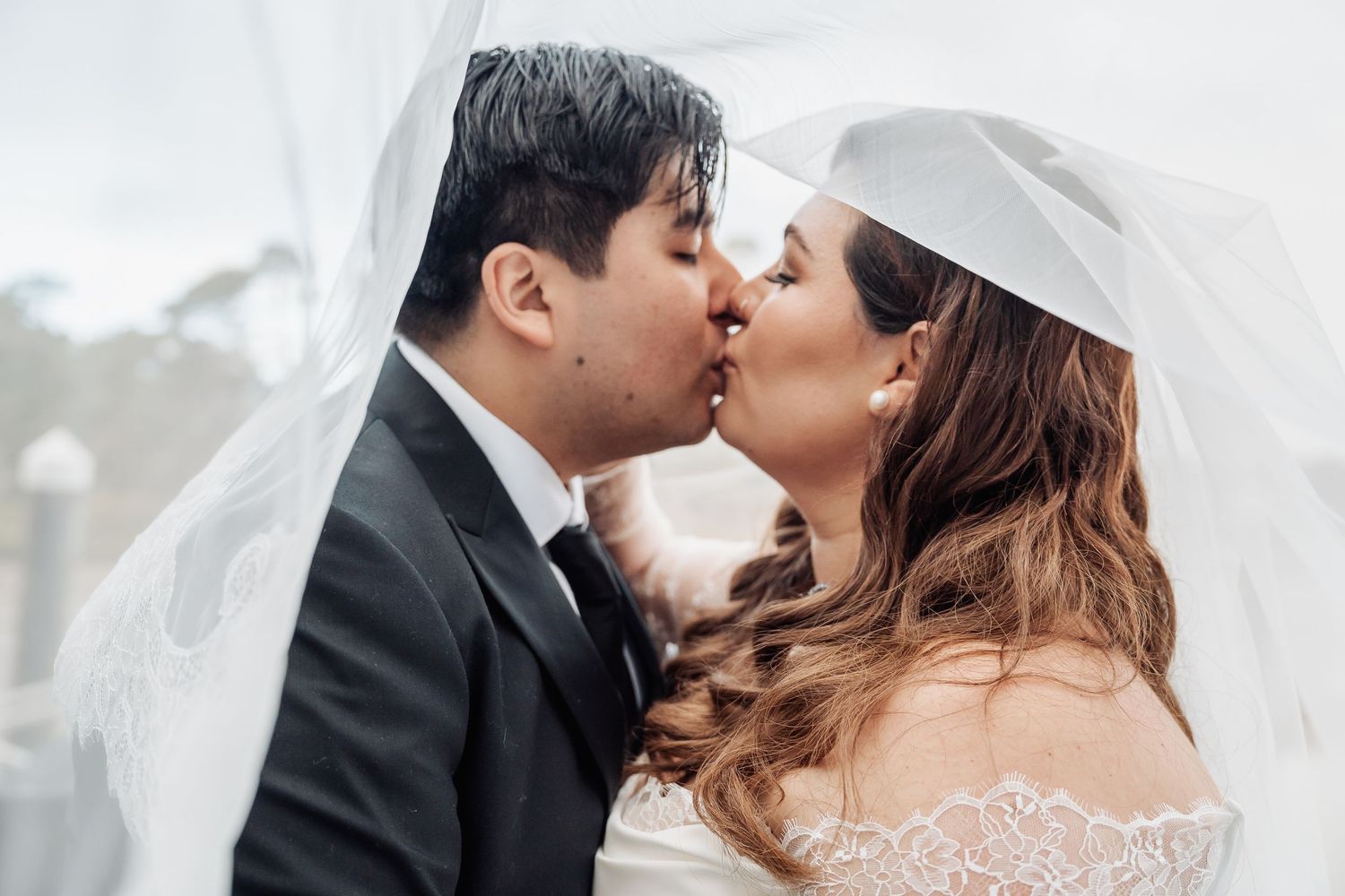 A couple shares a tender kiss during their wedding, with soft lighting and romantic ambiance creating an intimate moment.