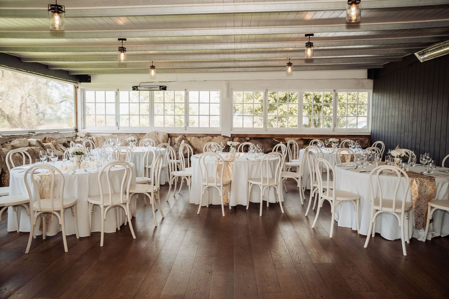 Spacious barn wedding venue interior with elegant table settings and natural lighting.