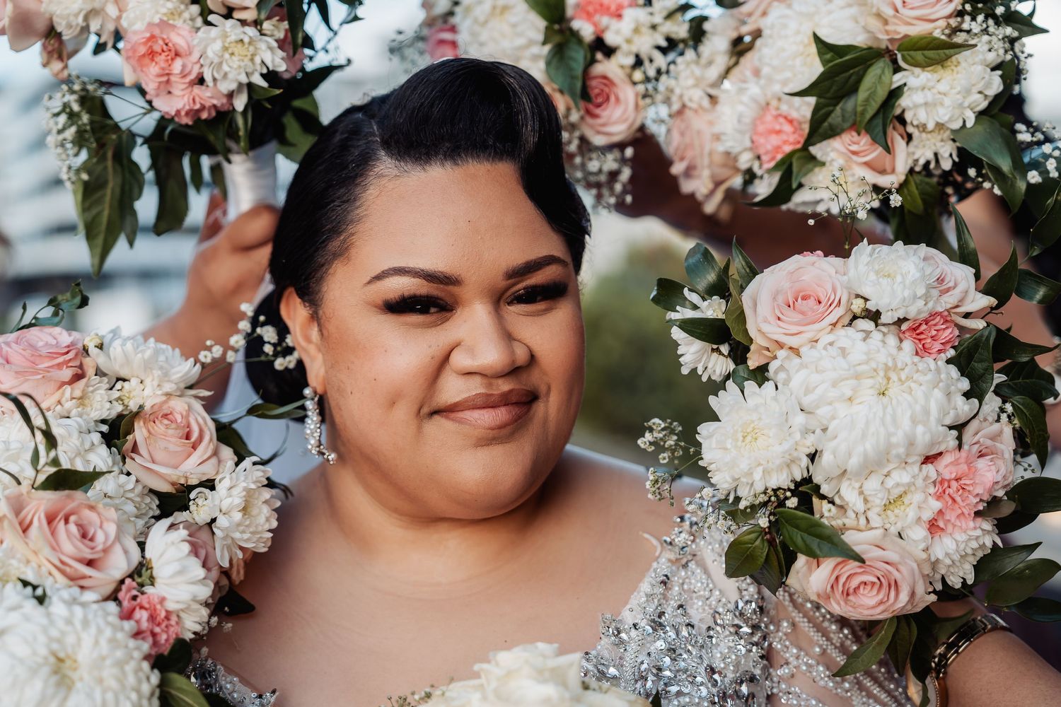 Close-up portrait of bride surrounded by pink and white roses and floral arrangements.