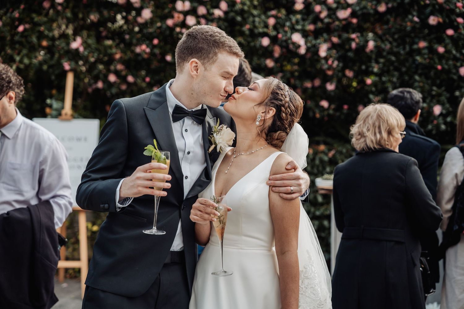 Elegantly dressed wedding guests share champagne toasts at an outdoor celebration.