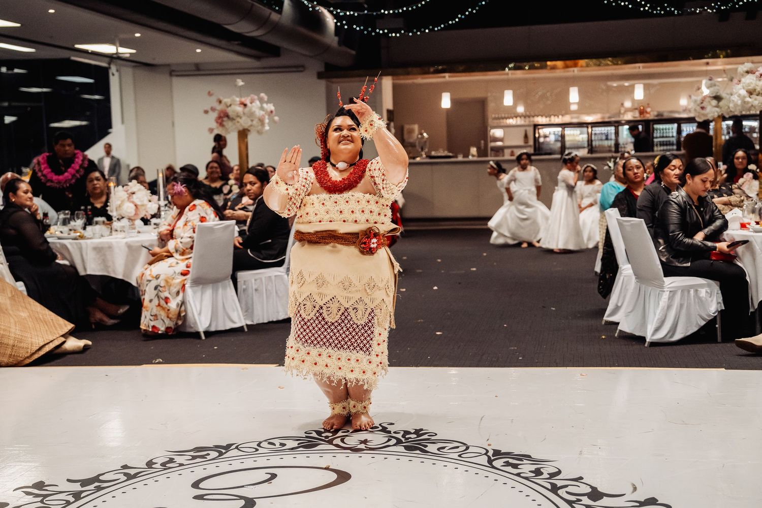 Wedding reception hall with patterned dance floor, white chairs, and elaborate decorations.