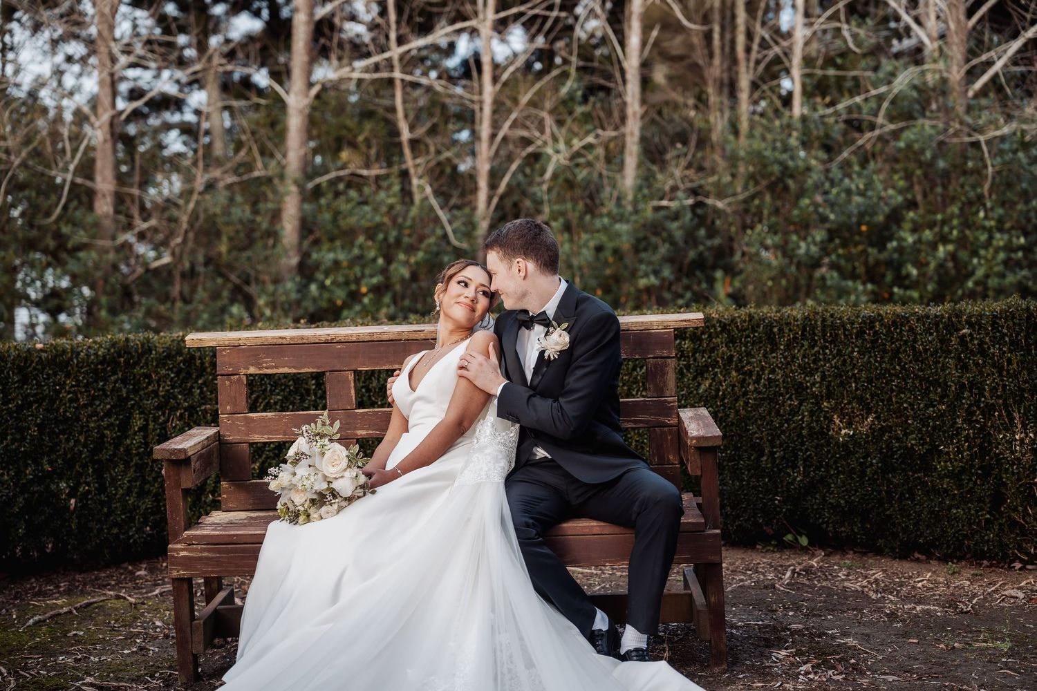 A romantic outdoor winter wedding scene with evergreen trees and garden benches.