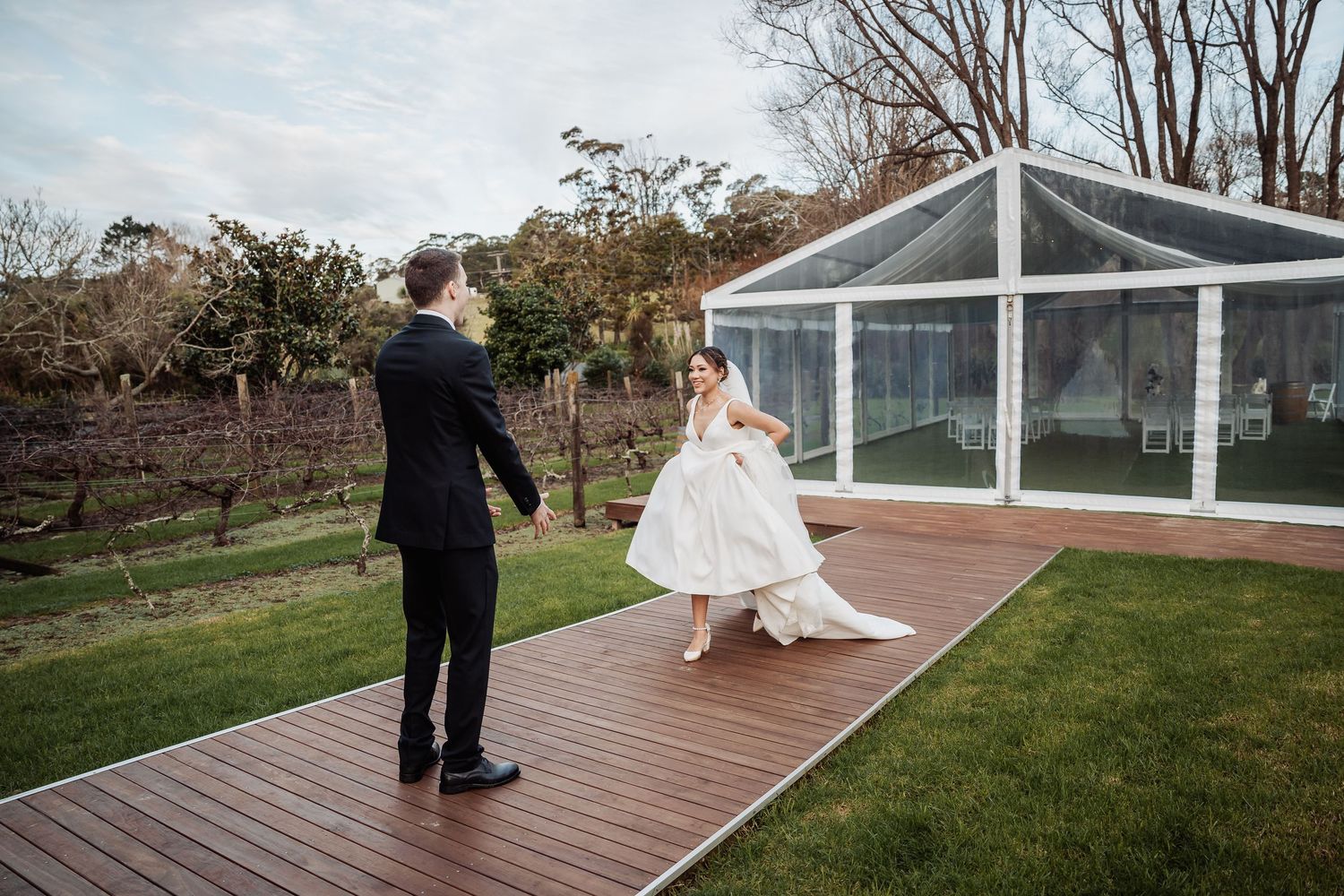 A couple poses on a wooden deck with a garden landscape in the background.
