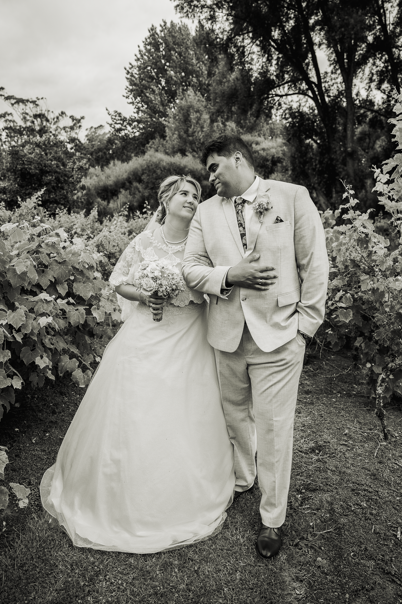 A black and white wedding portrait of a couple in a garden setting.