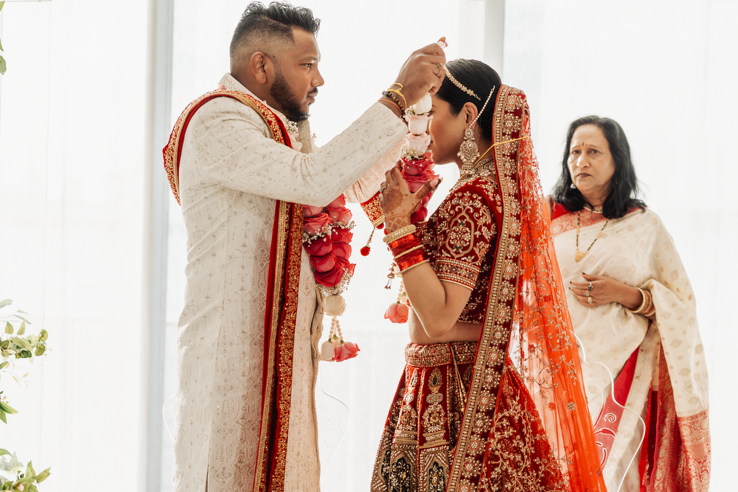 A traditional sindoor ceremony takes place during an Indian wedding with floral decorations.