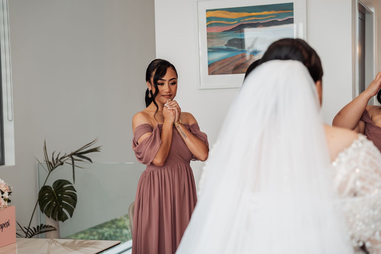 Wedding party preparations show intimate moments in a white and pink themed room.