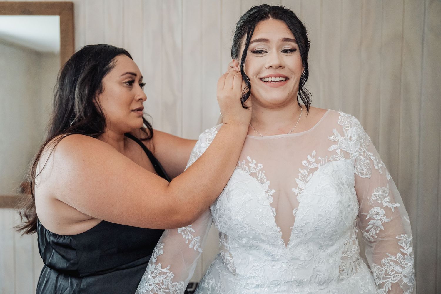 Wedding dress fitting shows intricate lace details and delicate finishing touches being adjusted before the ceremony.