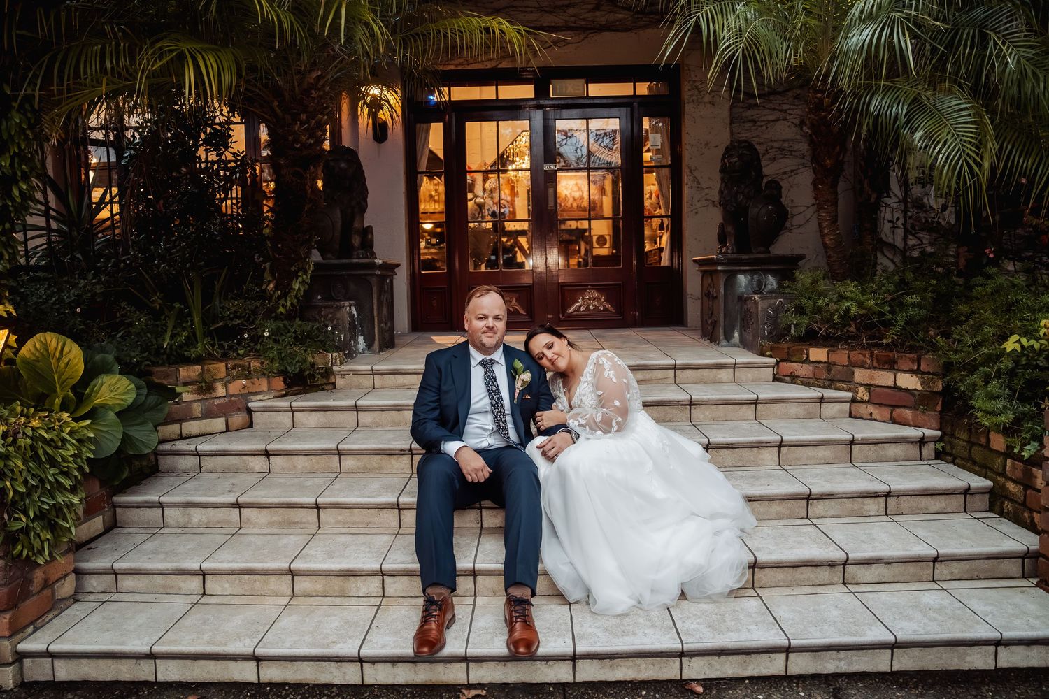 Elegant wedding venue steps decorated with palm trees and warm evening lighting.