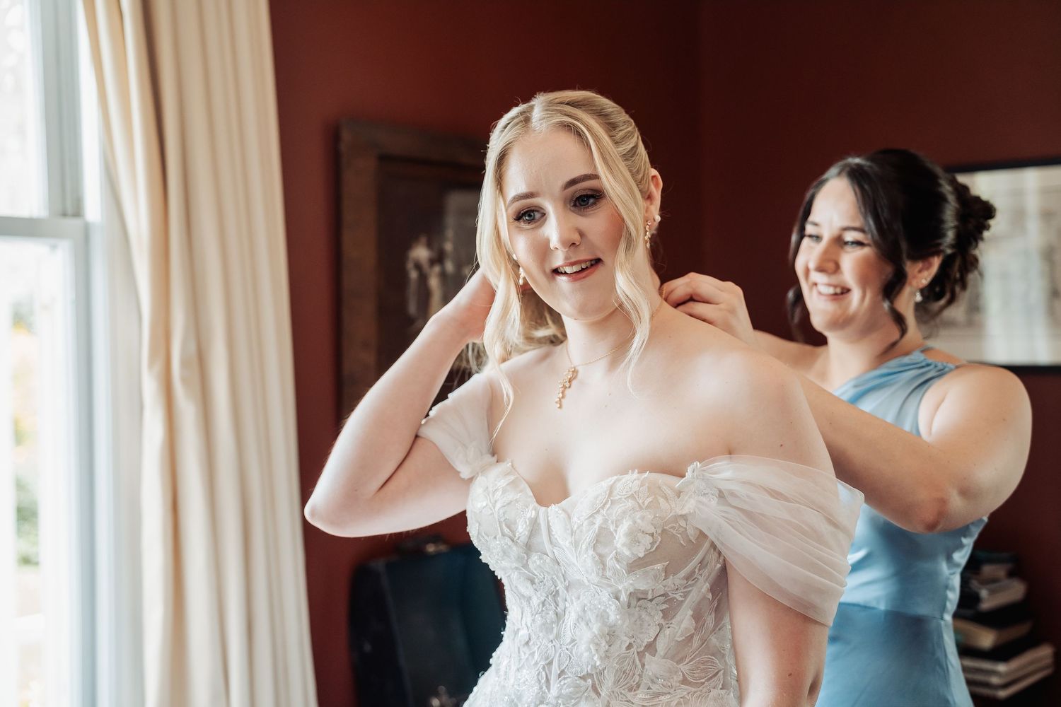 Wedding preparation scene in a room with warm lighting and white curtains.