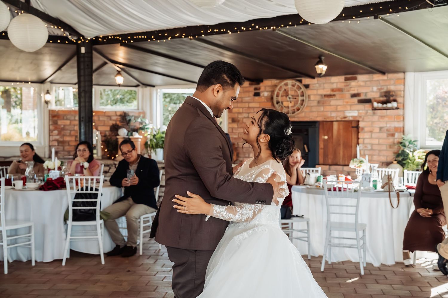 Bride and groom sharing their first dance at a warmly lit wedding reception.