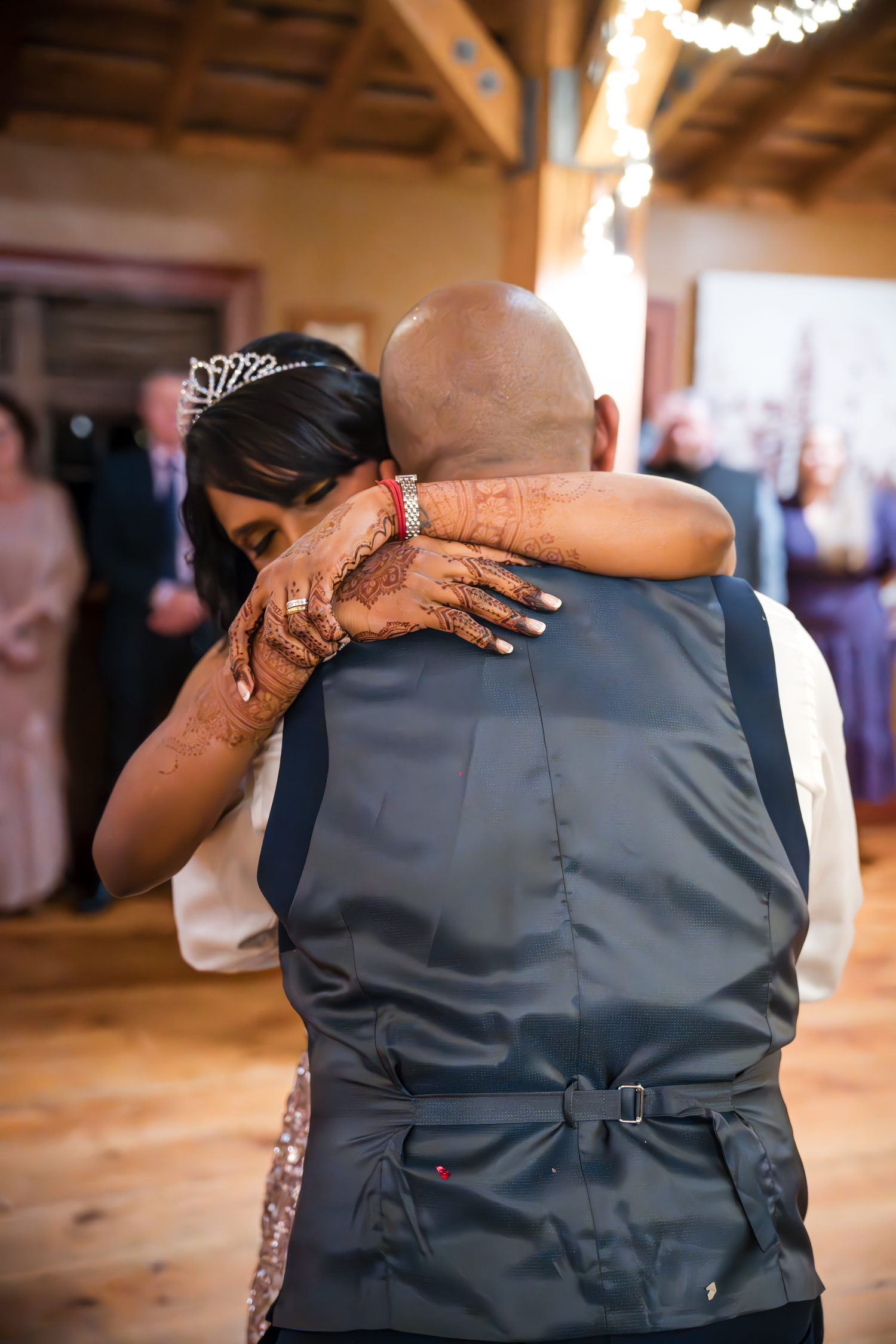 Emotional dance moment captured from behind at indoor wedding celebration.