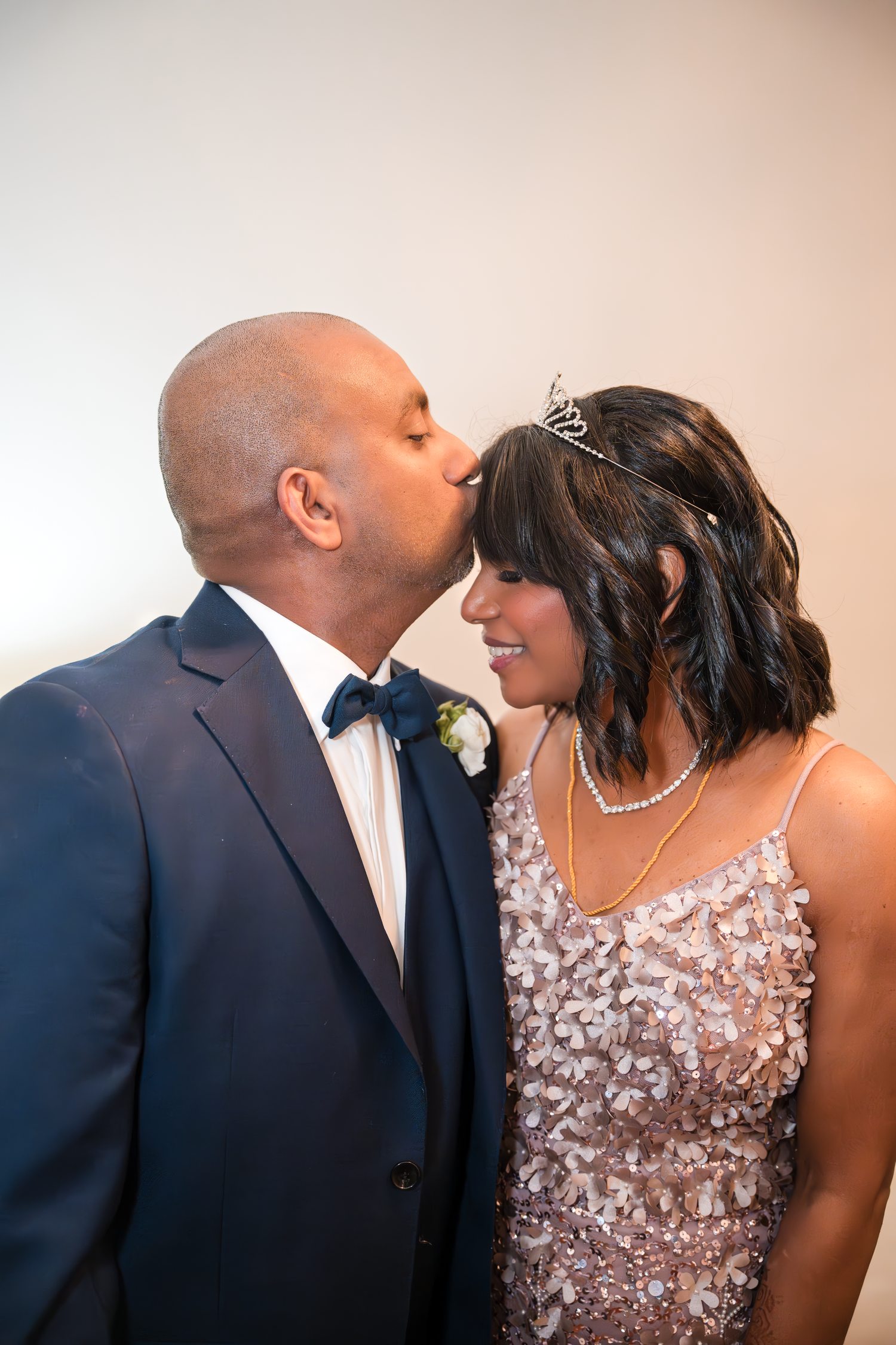 A tender moment between newlyweds, with bride wearing a sparkly dress and groom in dark suit.