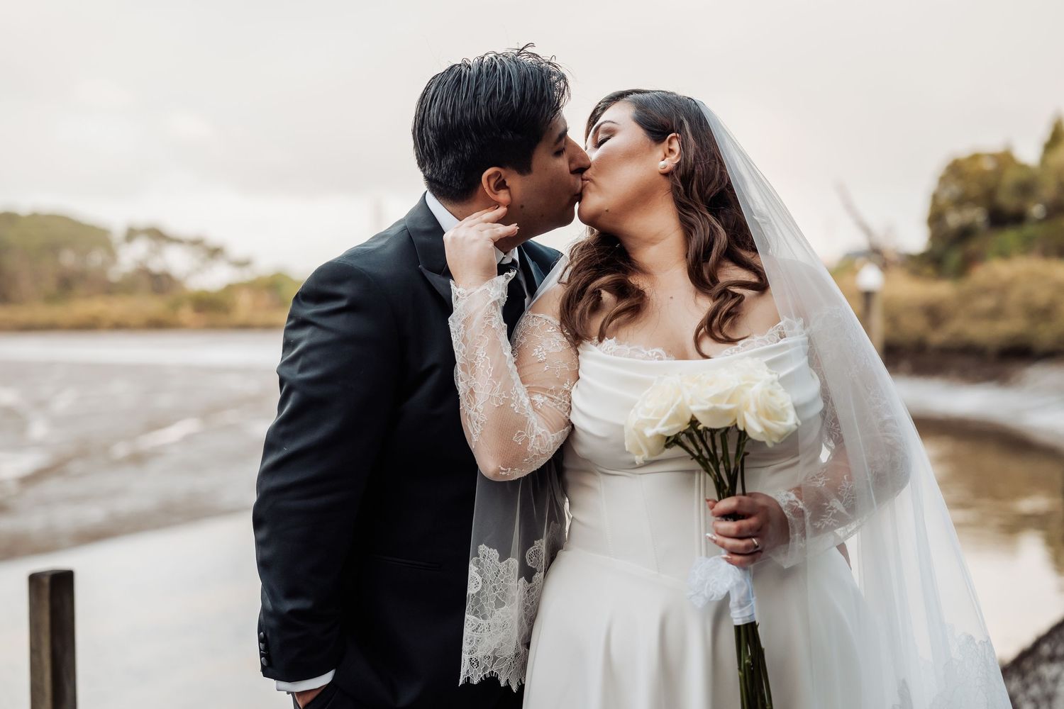 Romantic wedding photography captures intimate moments between the newlyweds along a scenic waterfront.