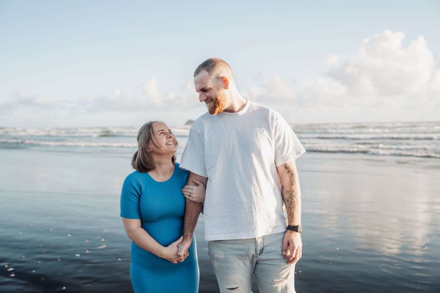 A couple walks together along a beautiful beach shoreline with blue skies and ocean views.