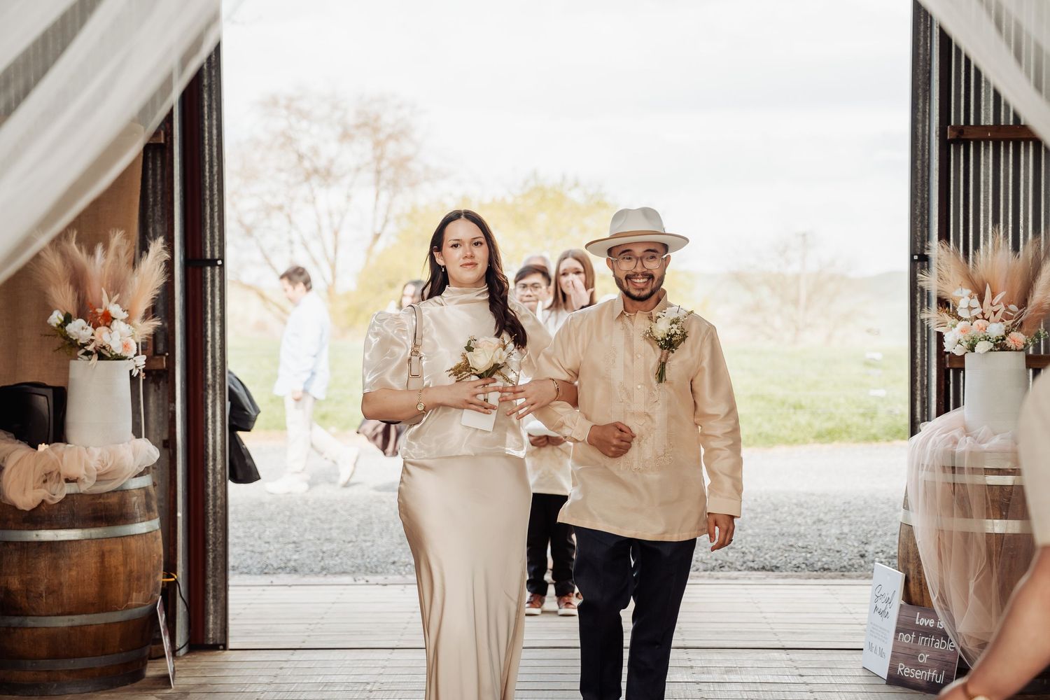 Wedding celebration in a rustic barn venue with neutral-toned attire.