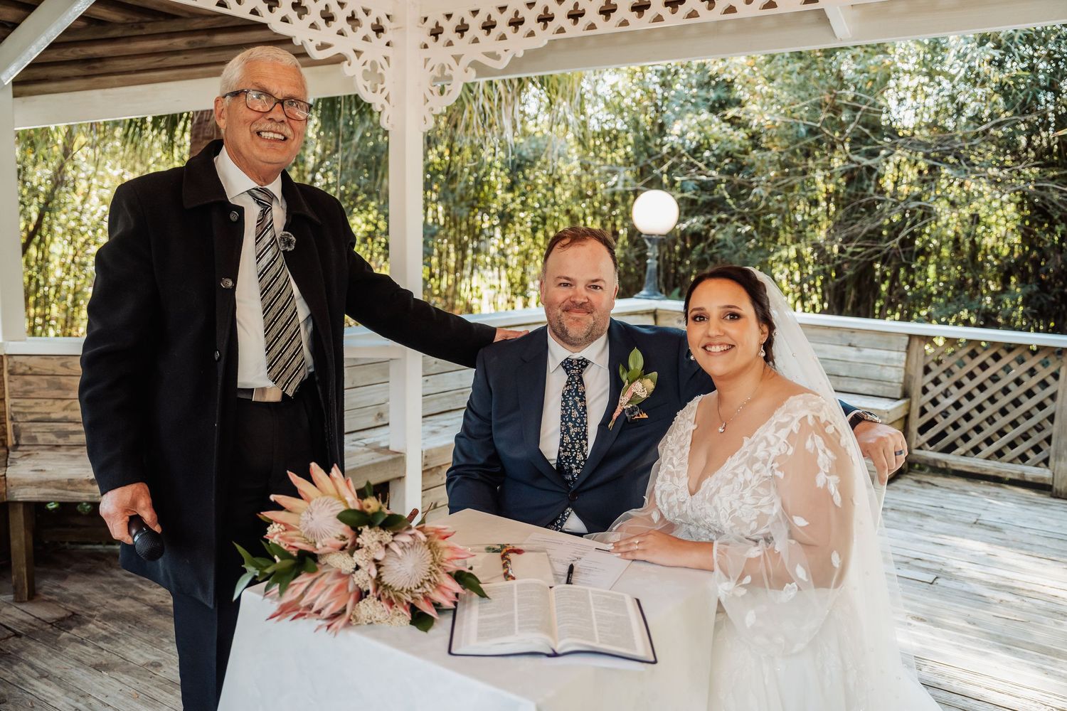 Wedding ceremony moments captured under a white gazebo decorated with string lights and greenery.