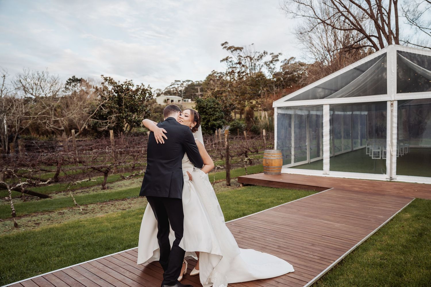 Wooden deck pathway leading to a white wedding gazebo surrounded by green landscaping.