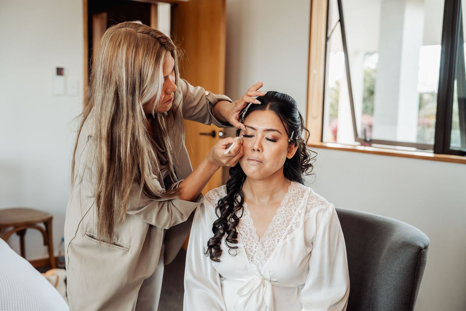 Wedding party getting ready in white robes while sitting on a couch in a bright indoor setting.