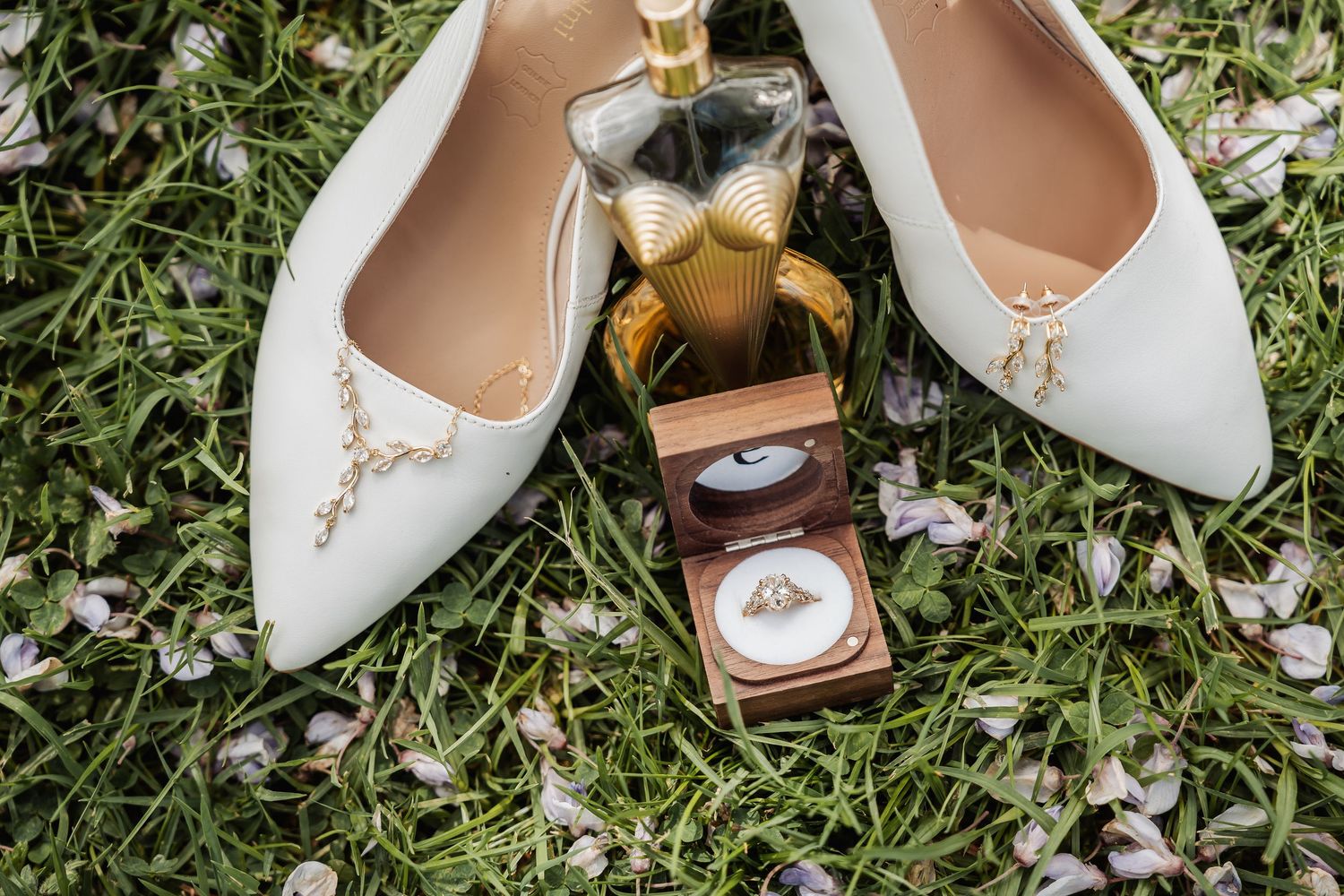 Elegant white bridal shoes displayed on green grass with natural outdoor lighting.