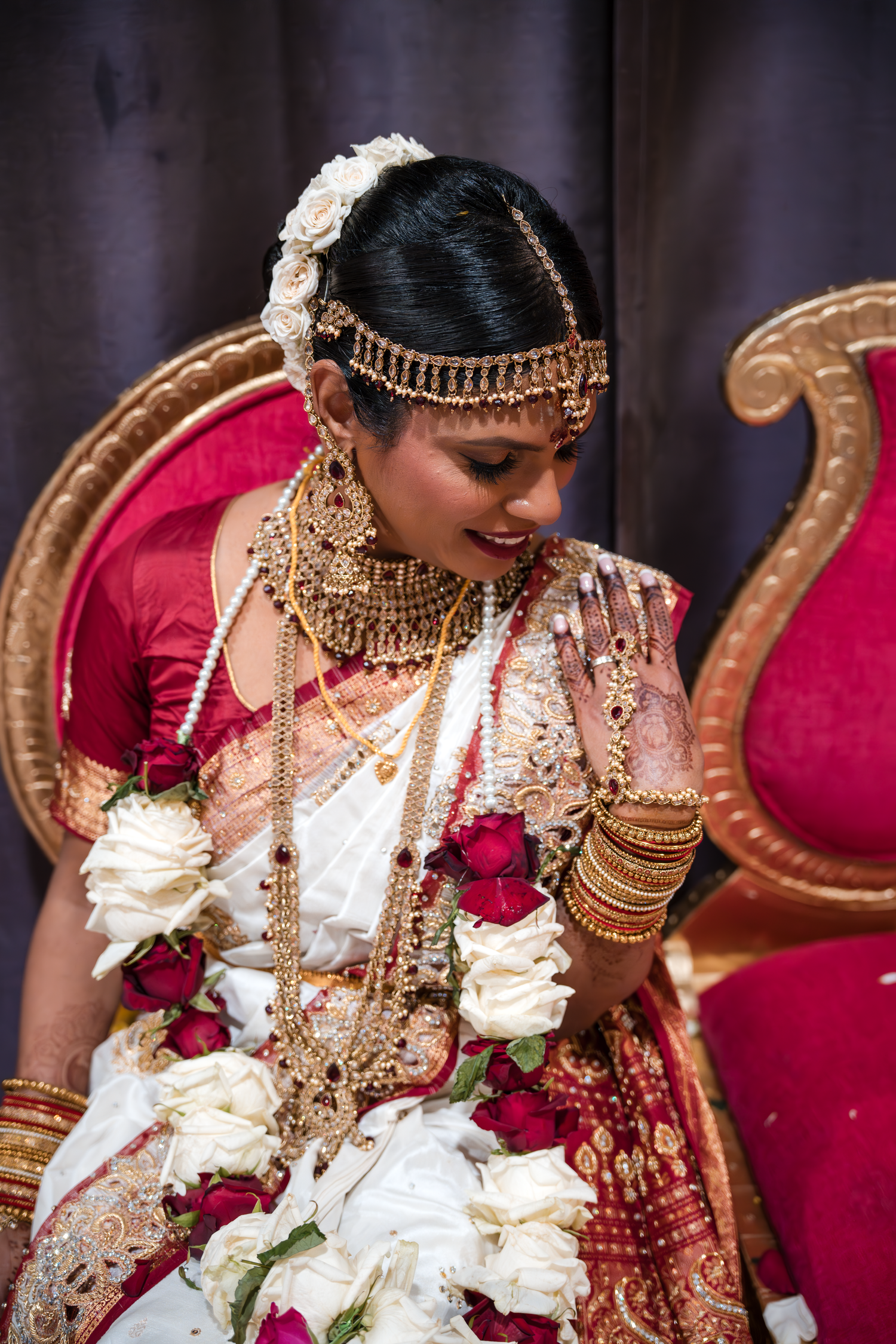 Close up of Indian bride wearing elaborate gold jewelry and traditional bridal attire.