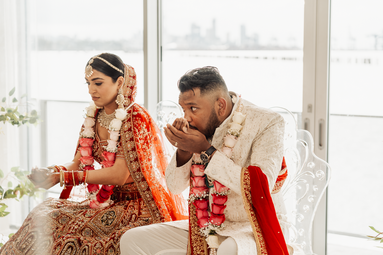 A candid moment during an Indian wedding ceremony with the couple seated at their mandap.