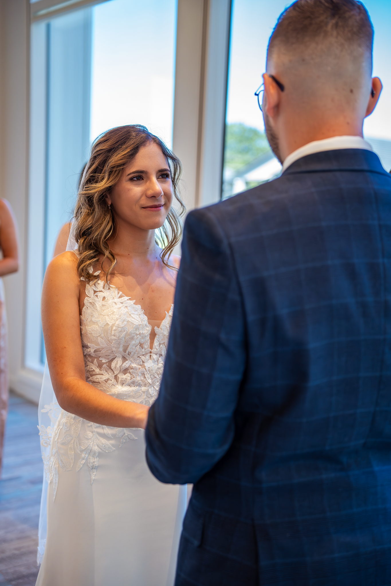 A tender moment during wedding vows in a bright, window-lit ceremony space.