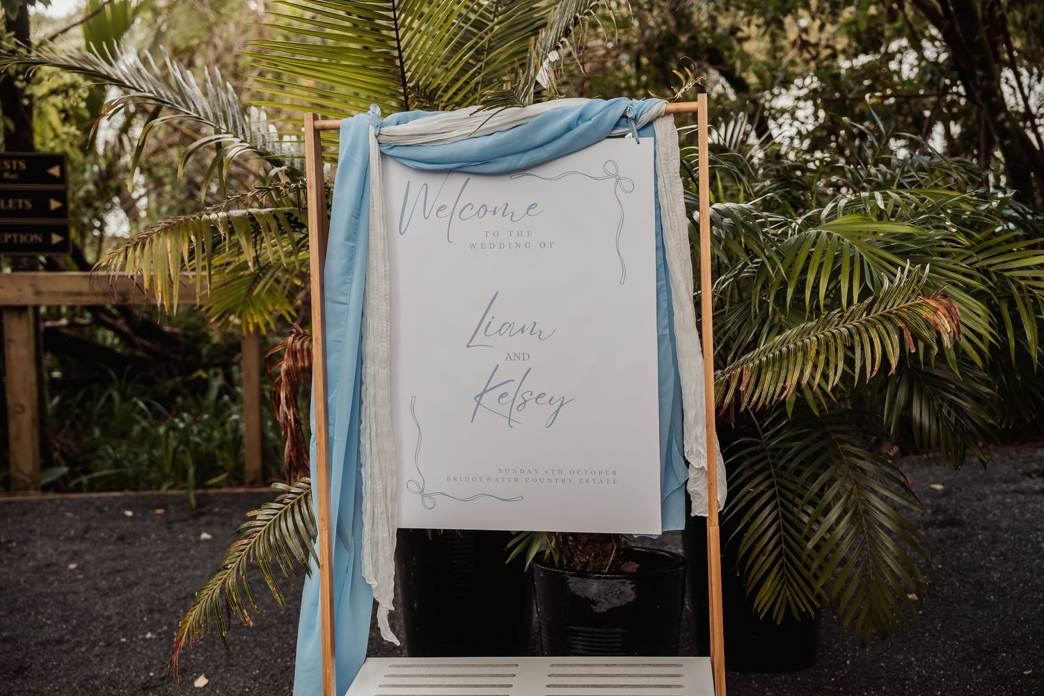 Light blue welcome signs displayed on wooden easels with palm trees in the background.
