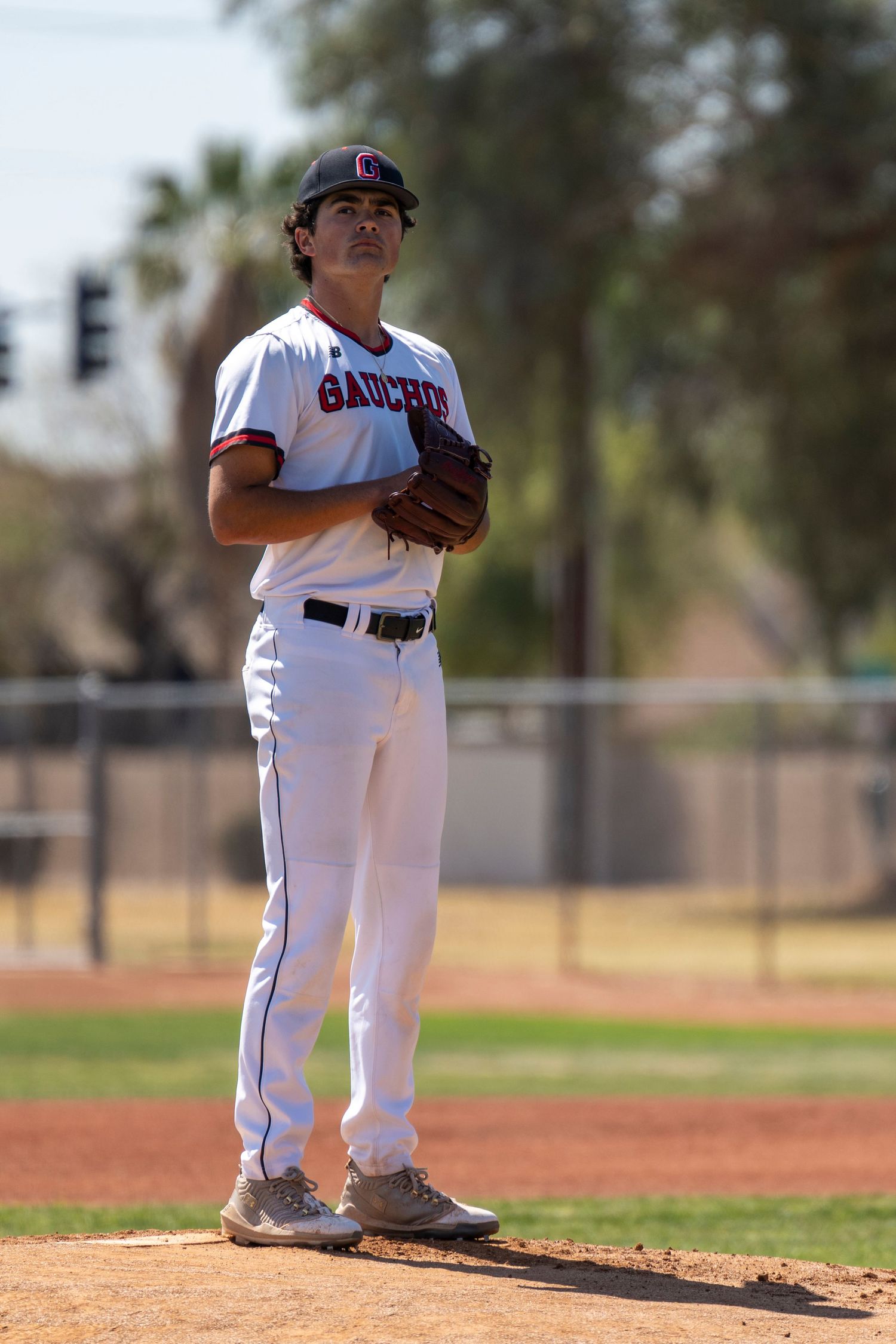 Baseball player who is standing on the mound getting ready to throw a pitch.