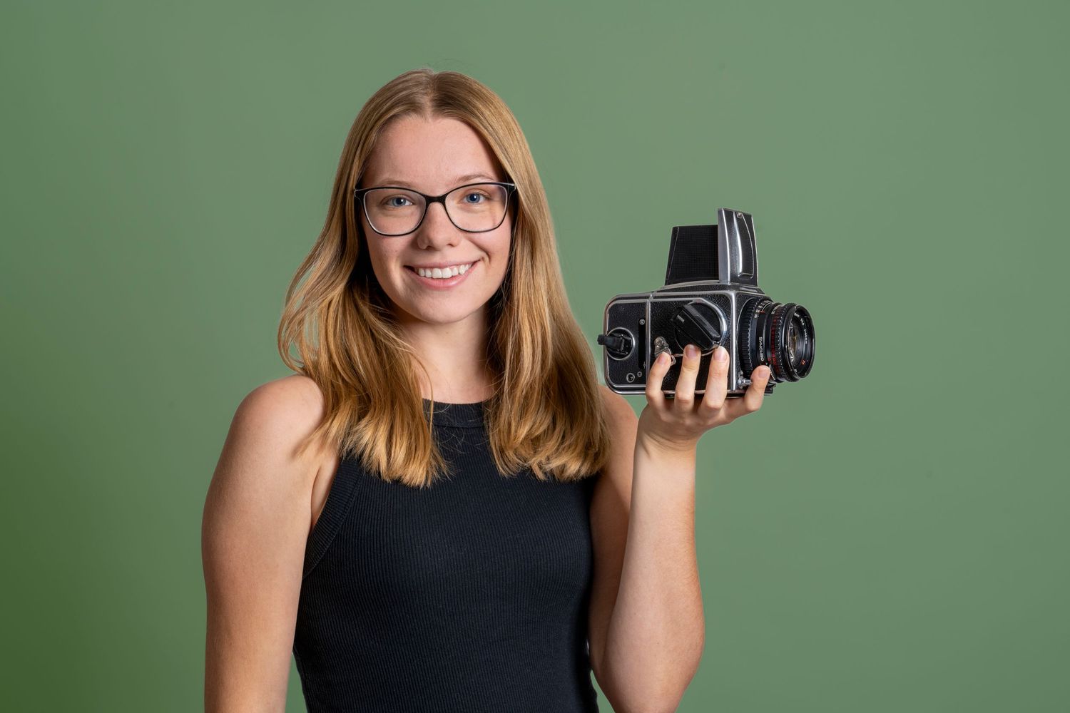 Danielle Gantt holding a Hasselblad camera in her hand and smiling.