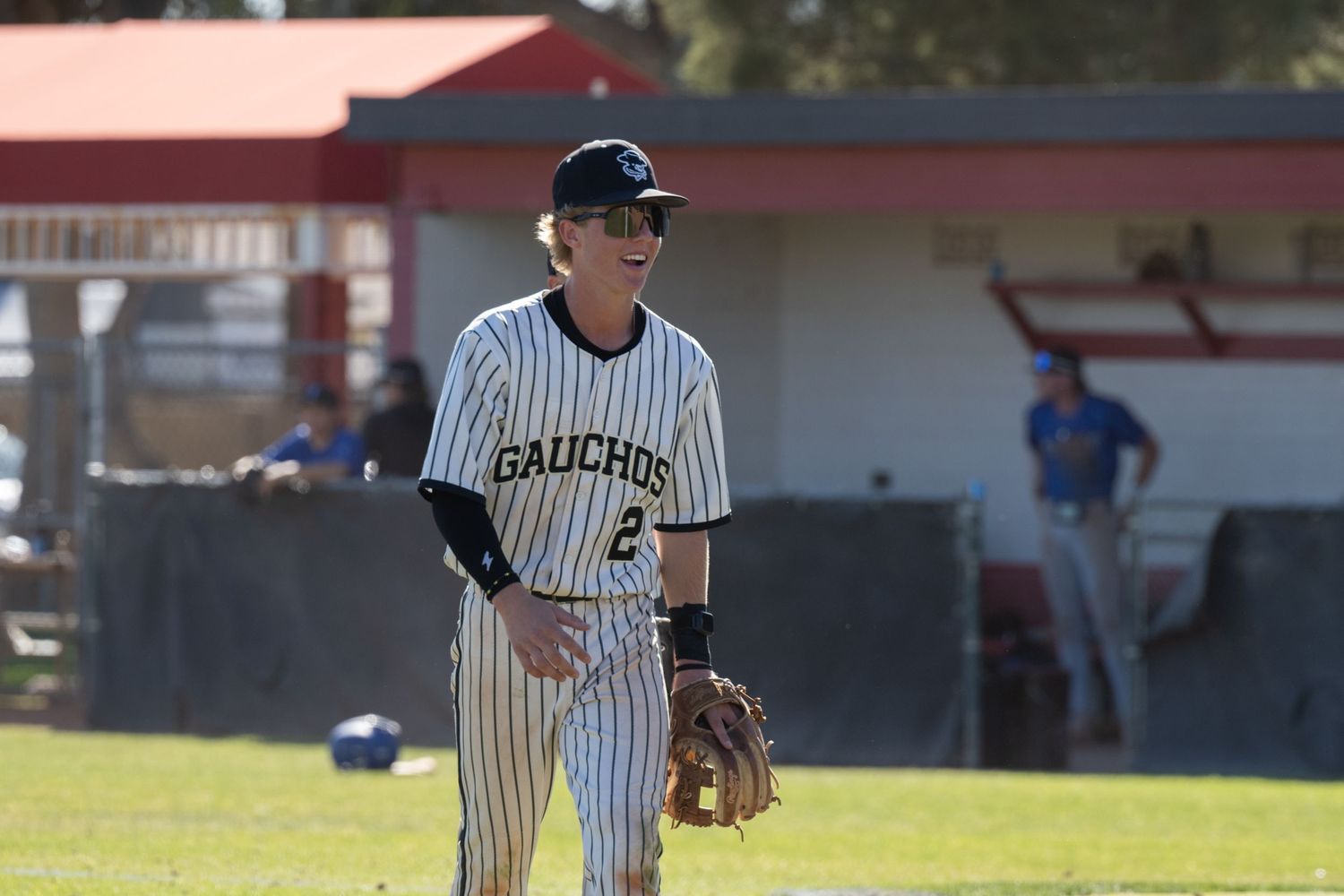 A baseball player walking off field while smiling and laughing.