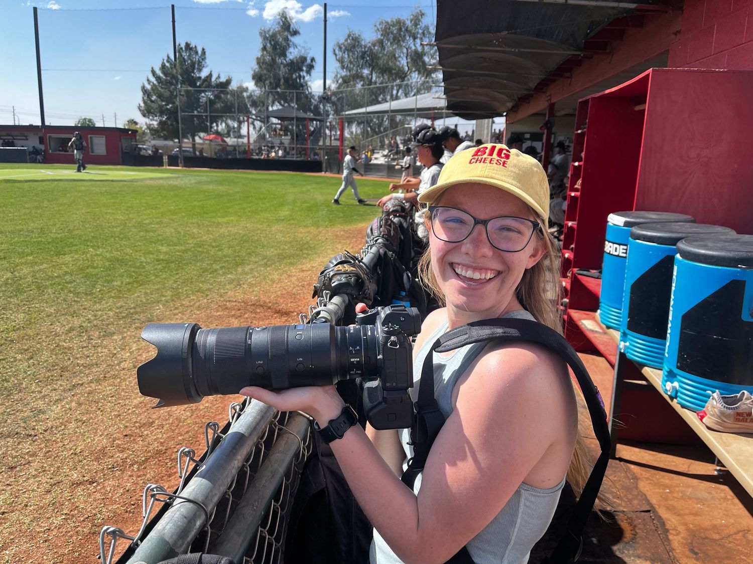 Danielle Gantt smiling while holding her camera in the dugout at a GCC Baseball game.