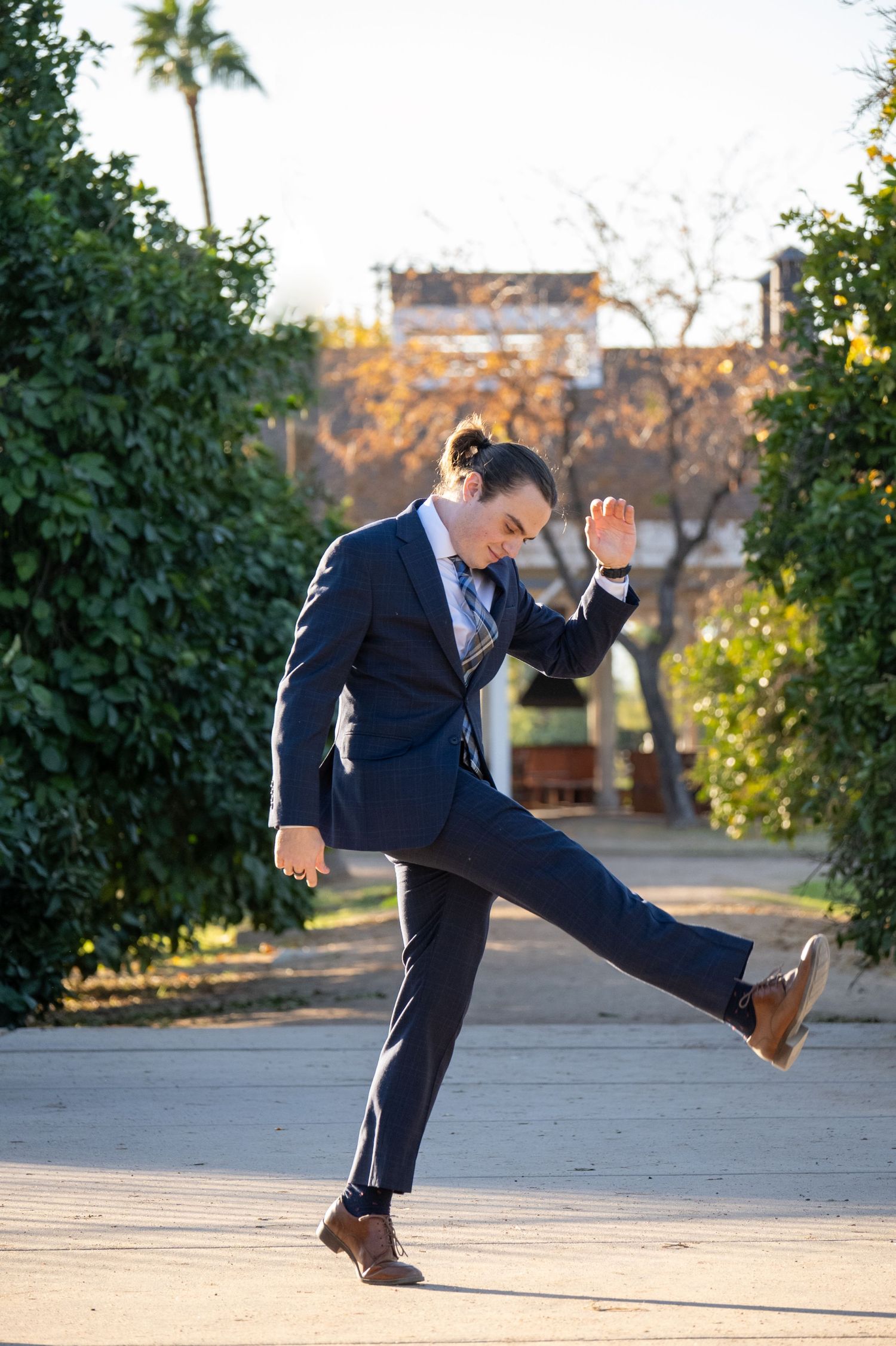 Man turned to the side, kicking his leg up and smiling.