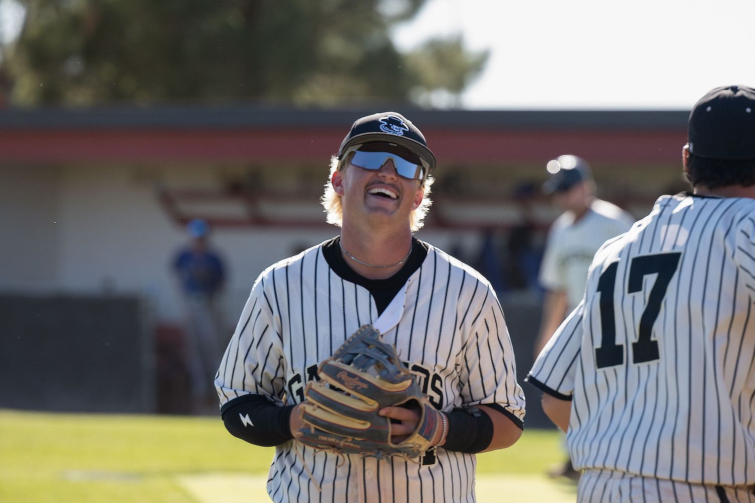 A baseball player walking off field while smiling and laughing.