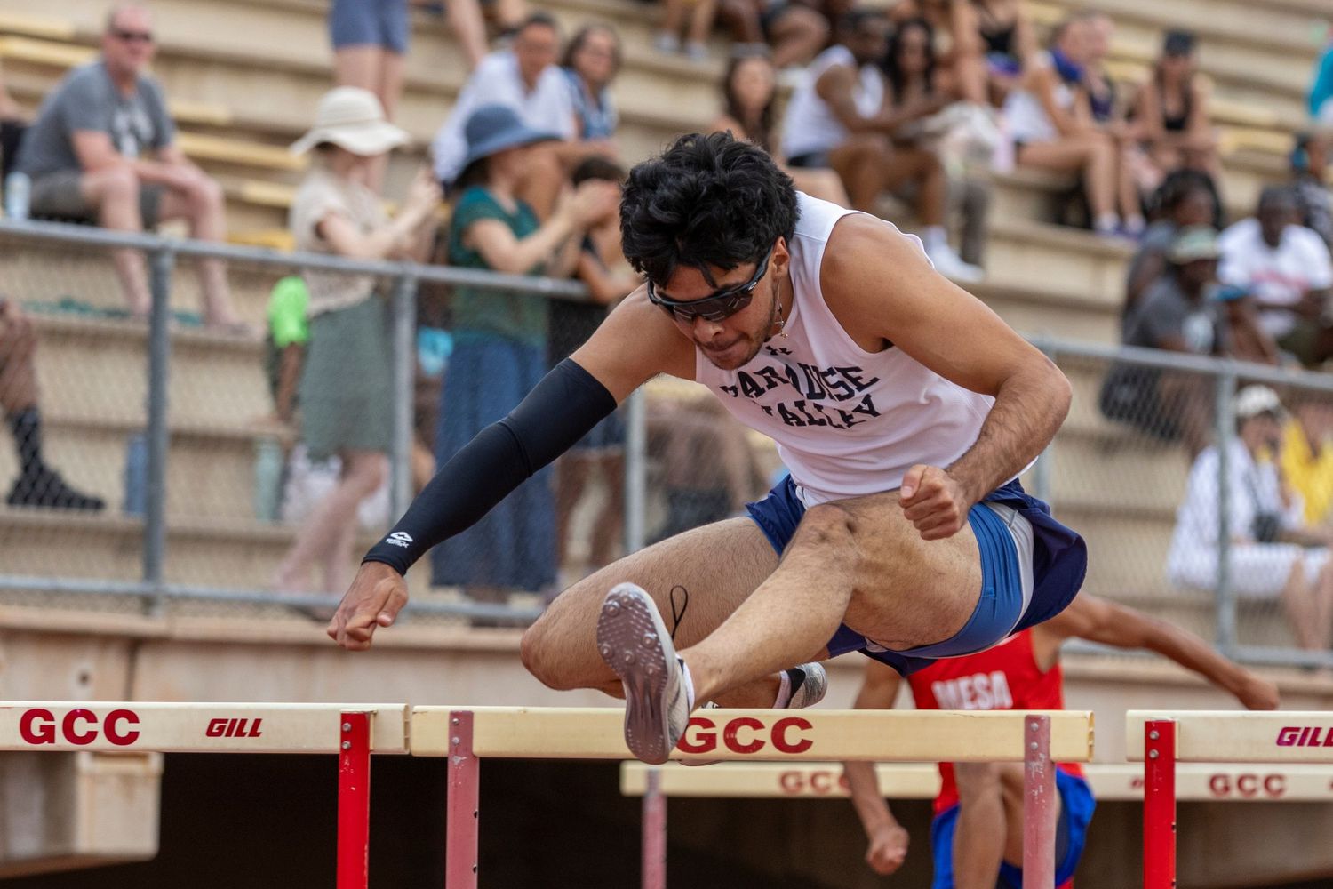 Track runner, jumping over a hurdle.