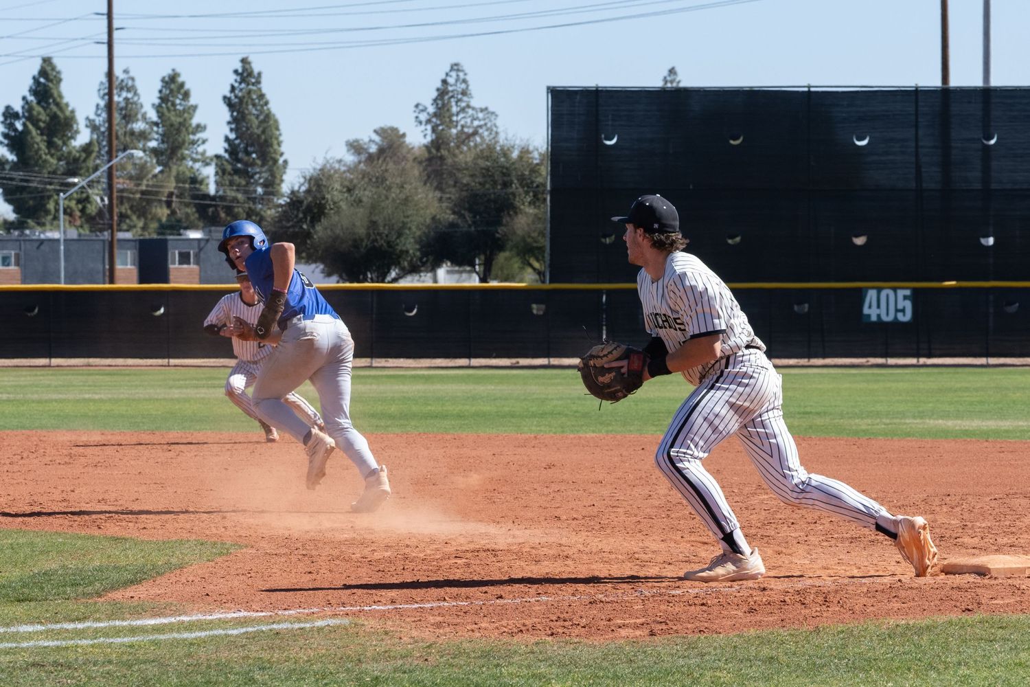 Baseball player on base one who caught the ball and a player on the other team running away from him.