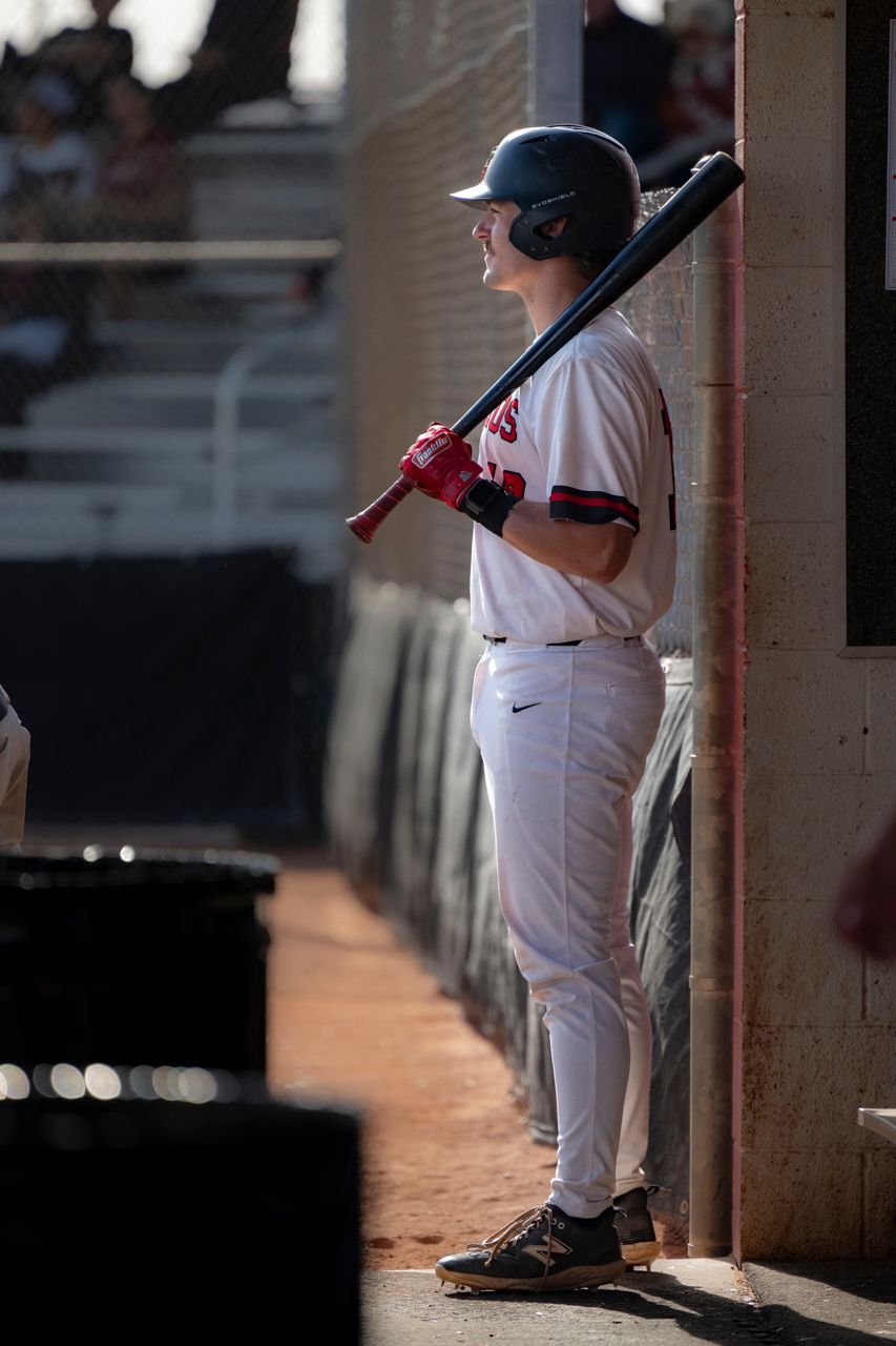 Baseball player standing at the dugout entrance getting ready to bat.