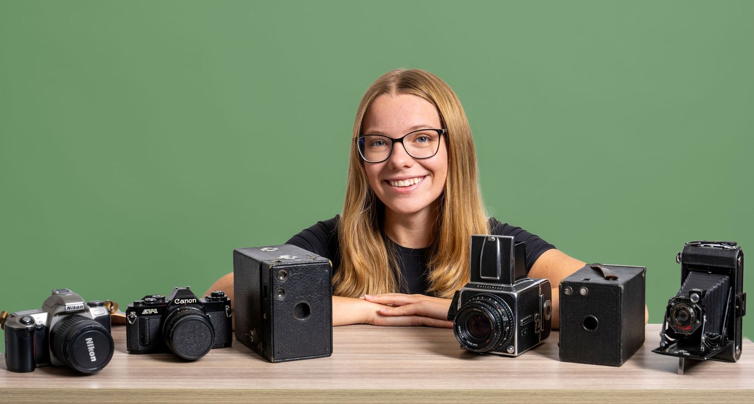 Danielle Gantt smiling with her collection of old cameras.