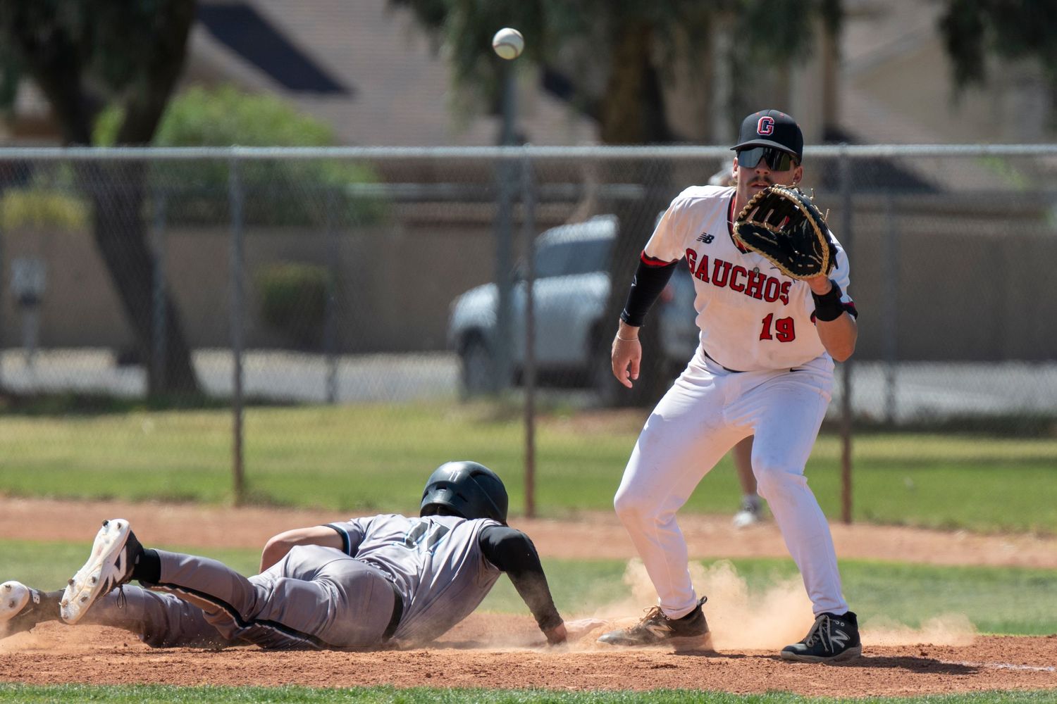 Baseball player diving to first base as another baseball player catches the ball.