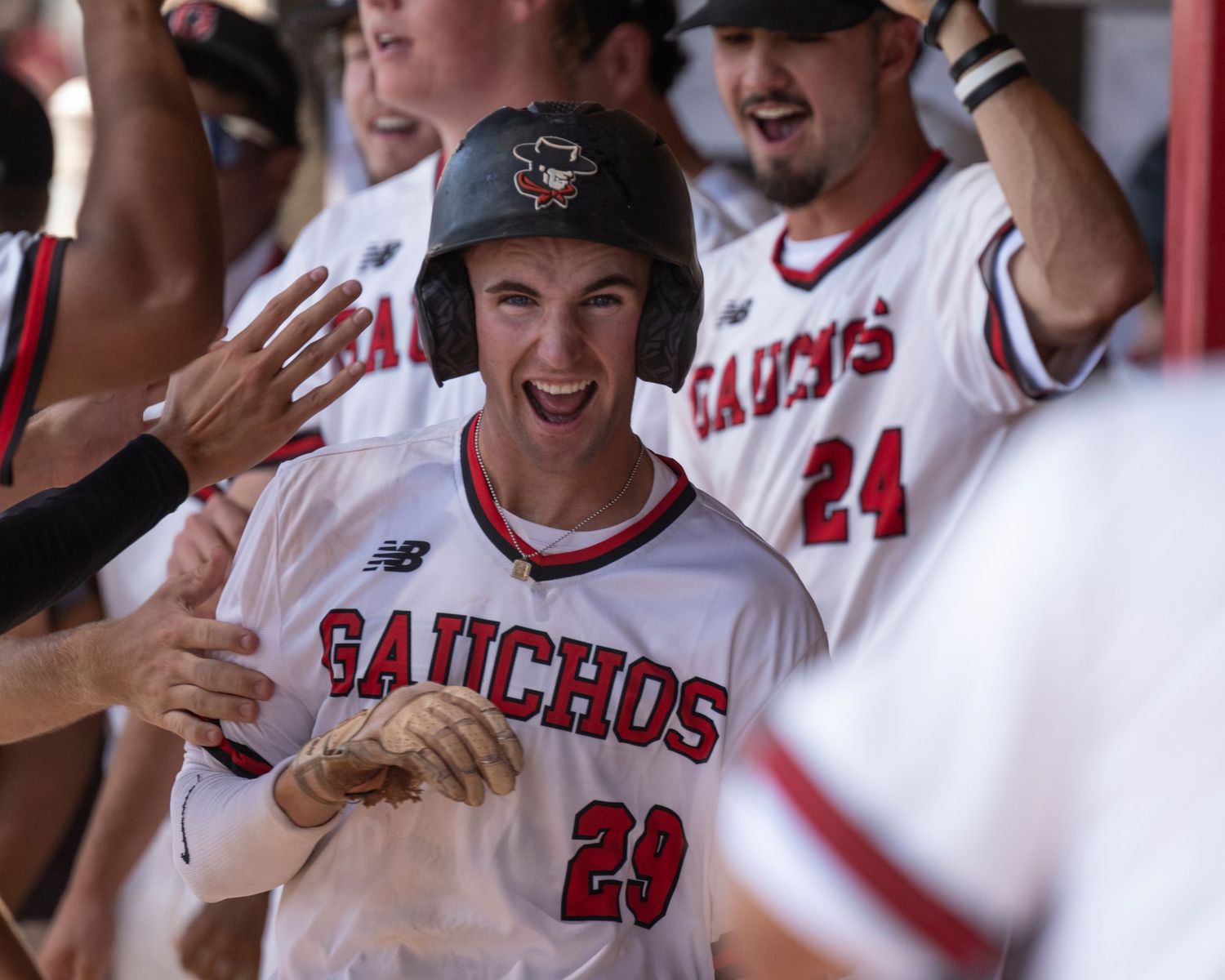 Baseball player smiling and walking through a crowd of his teams excited.
