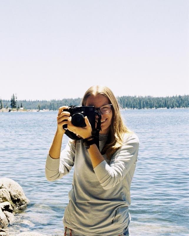 Danielle Gantt taking a photo with a Film Camera at a lake.